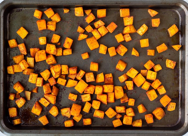 Roasted butternut squash with cinnamon and maple syrup on a baking sheet