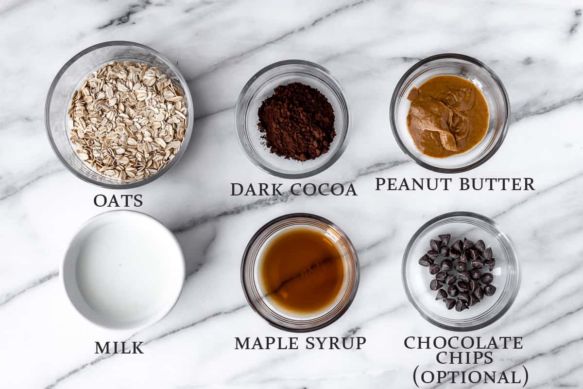 Ingredients to make dark chocolate peanut butter oatmeal on a marble background with text overlay.
