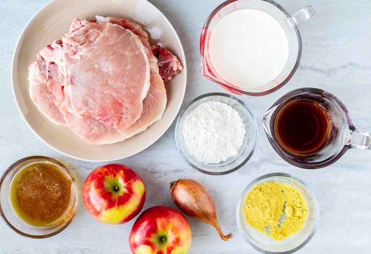 Ingredients to make maple apple pork chops in glass bowls and sitting on a white background