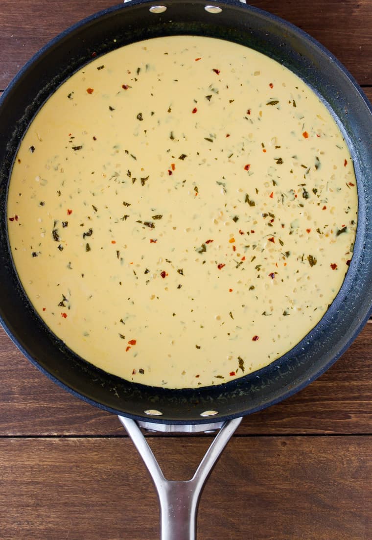 Overhead View of Creamy Cilantro Lime Sauce Cooking in a Black Skillet Over a Wood Background
