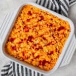 Overhead view of a buffalo chicken cauliflower casserole in a white, square casserole dish over a blue and white striped linen.