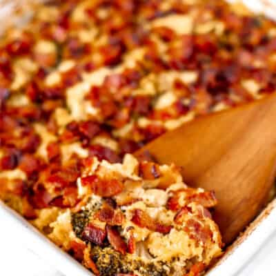 Cheesy Chicken and Broccoli casserole with bacon on top and a wood spoon lifting some up with text overlay.