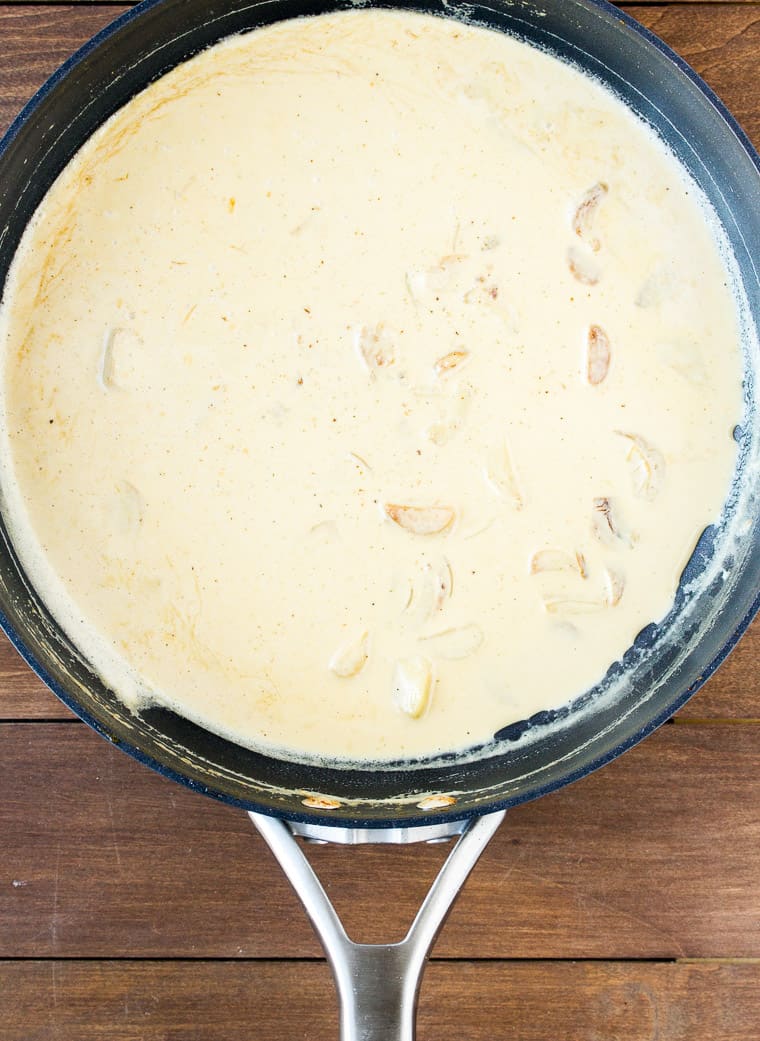 Garlic Cream Sauce in a Black Skillet on a Wood Background