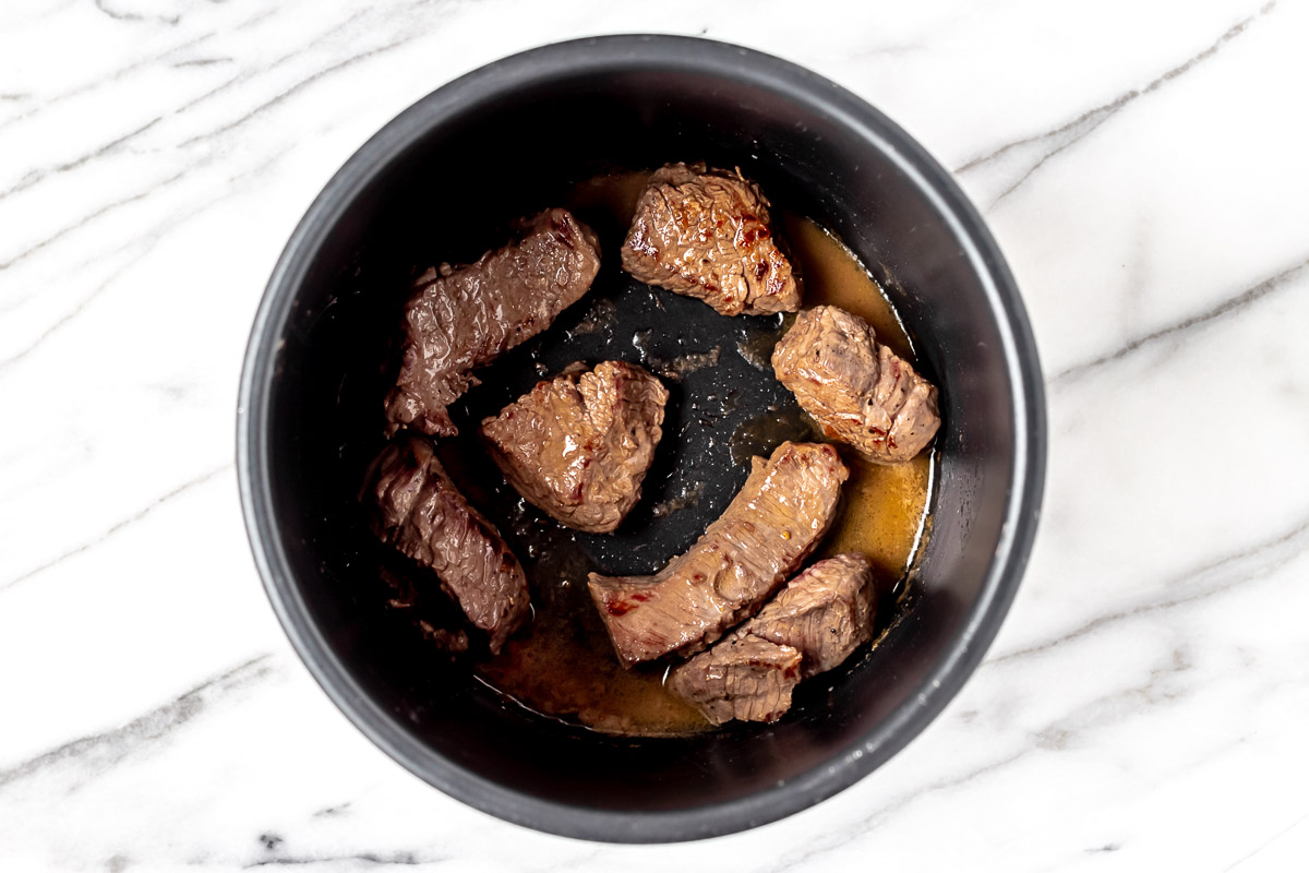 Browned boneless short ribs in the bottom of an Instant Pot.