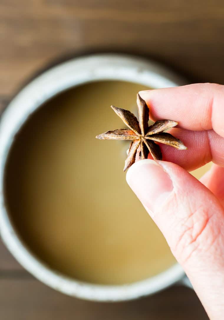 Holding a Piece of Star Anise Over the Mug of Chai Tea Latte