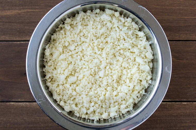 Riced cauliflower in a silver bowl on a wood background