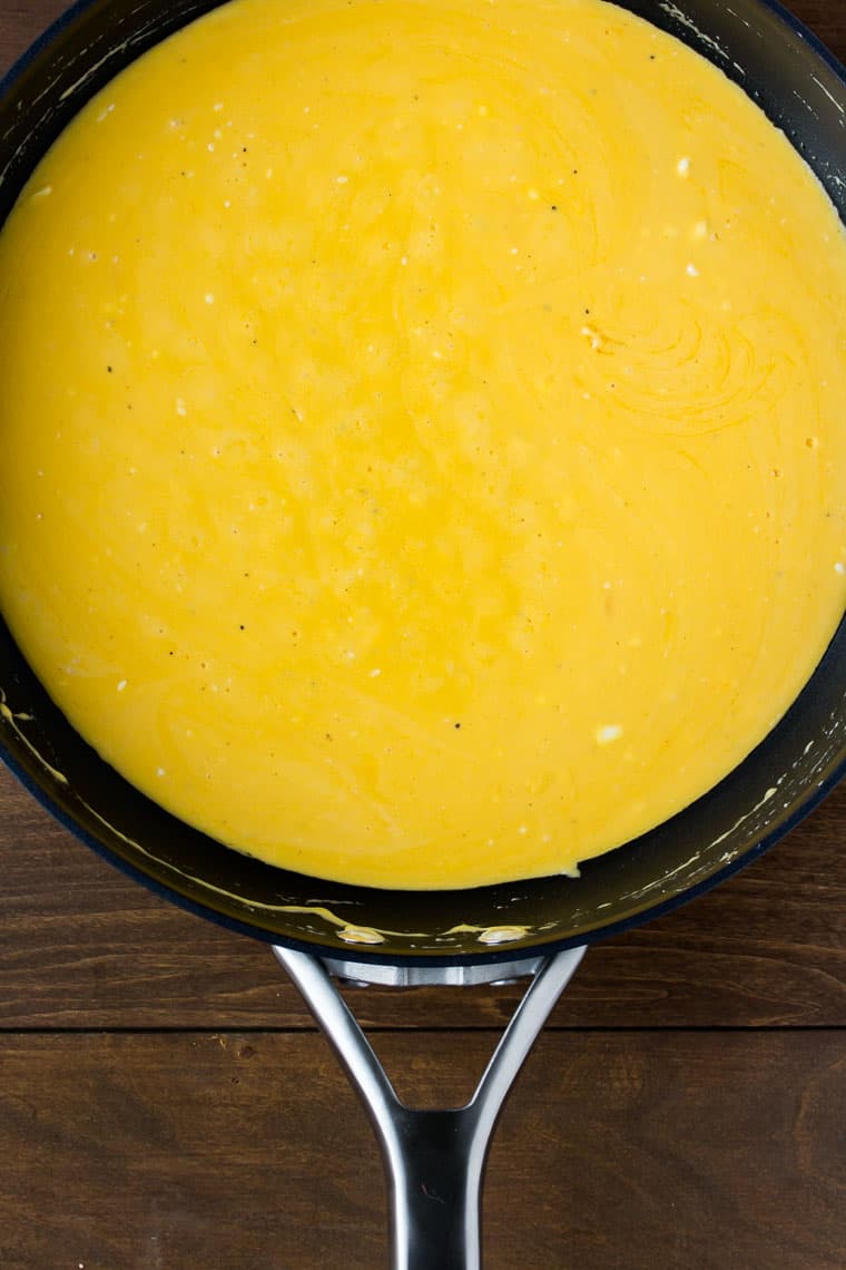 Orange cheese sauce in a black skillet over a wood backdrop
