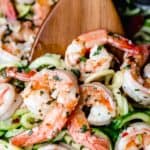 Close up of keto shrimp scampi and zucchini noodles being lifted up with a wood spoon