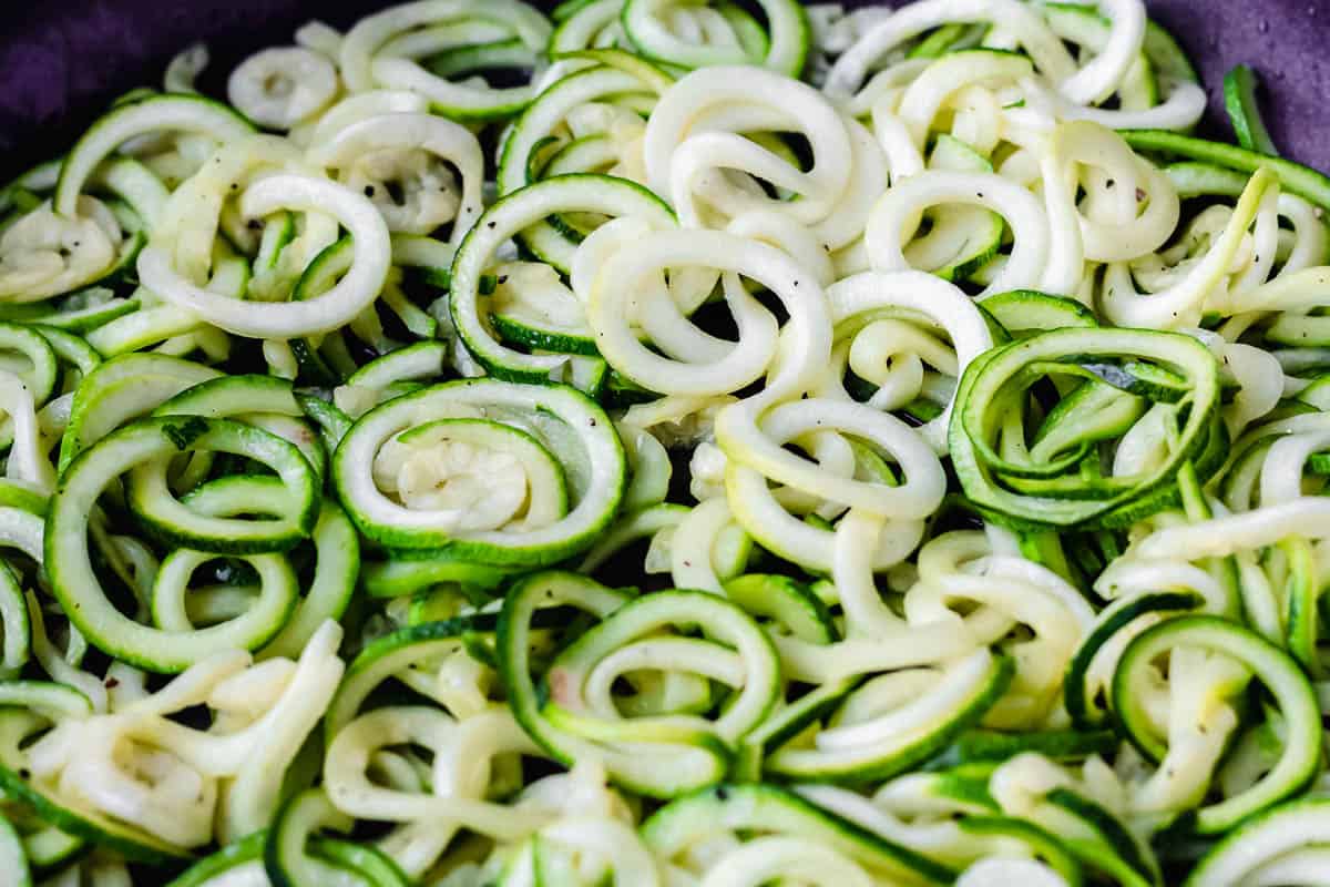 Zucchini noodles cooking in a black skillet