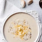 a bowl of white cheddar cauliflower soup with text overlay