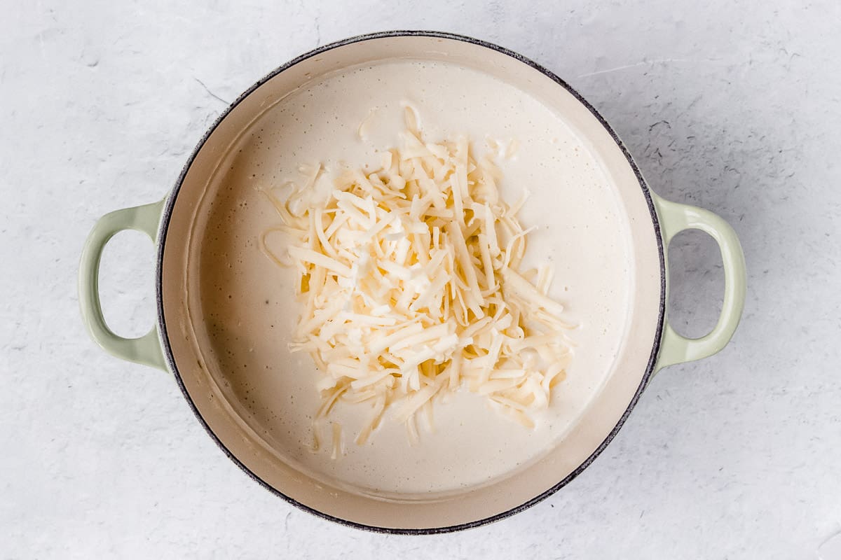 Pureed cauliflower soup with white cheddar cheese over a white background
