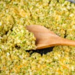 Cheddar Broccoli Cauliflower Rice in skillet with a wood spoon