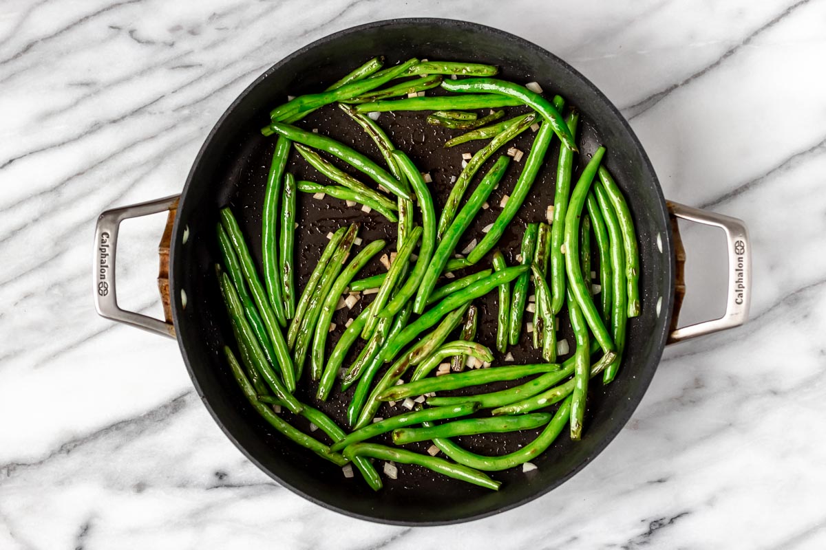 Garlic and green beans cooking in a skillet.