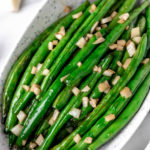 Honey garlic green beans in an oblong bowl with text overlay.