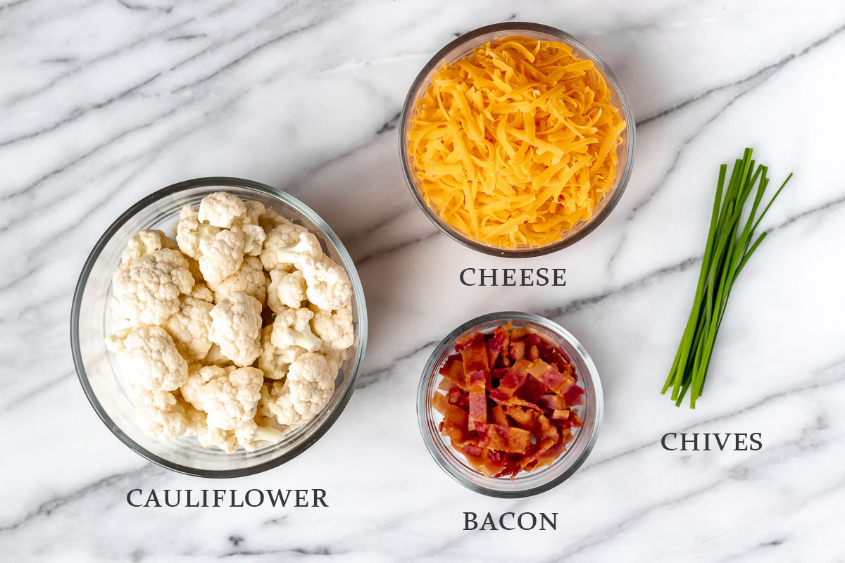 Ingredients to make loaded cauliflower bites on a marble background with text overlay.