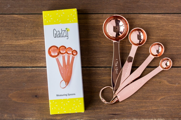 Giadzy Copper Measuring Spoons and the box they came in on a wood backdrop 