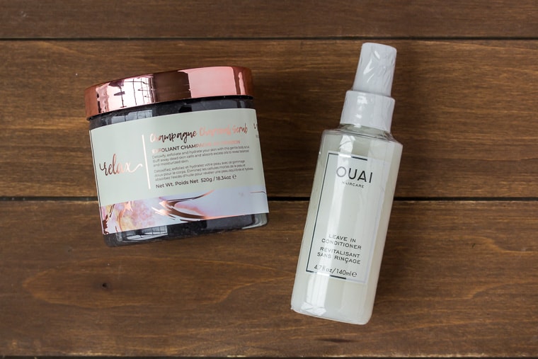 Ouai Leave In Conditioner and Manna Kadar body scrub on a wood backdrop