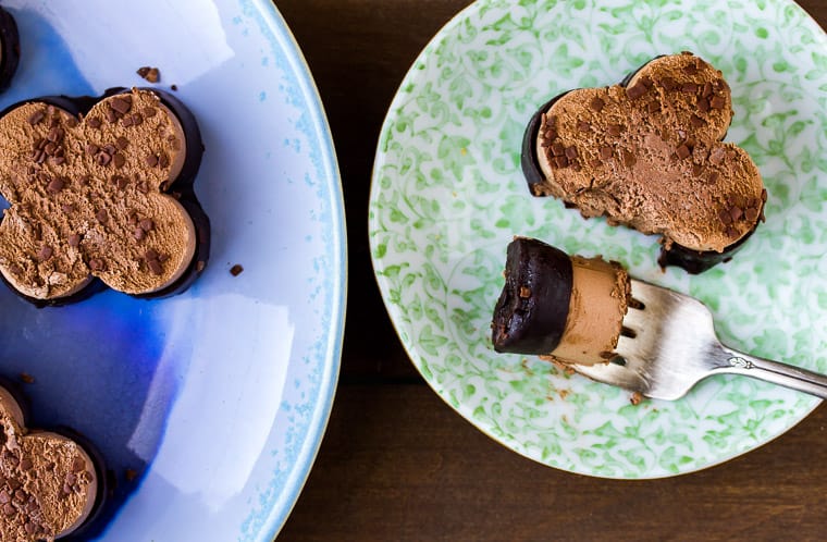 Mini Chocolate Mousse on a blue serving plate with one on a small green dessert plate with a forkful taken out sitting next to it