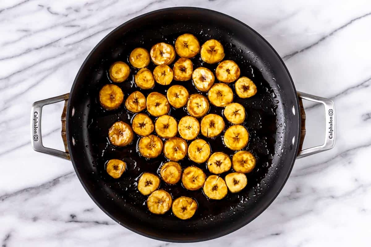 Fried plantain coins in a skillet.