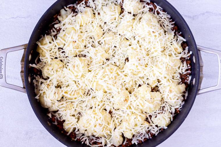 Italian ground beef and cauliflower skillet topped with cheese before baking over a white background