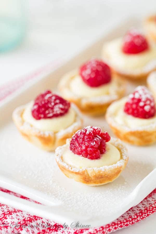 Mini Raspberry Tarts on a white serving tray with a red and white napkin under it