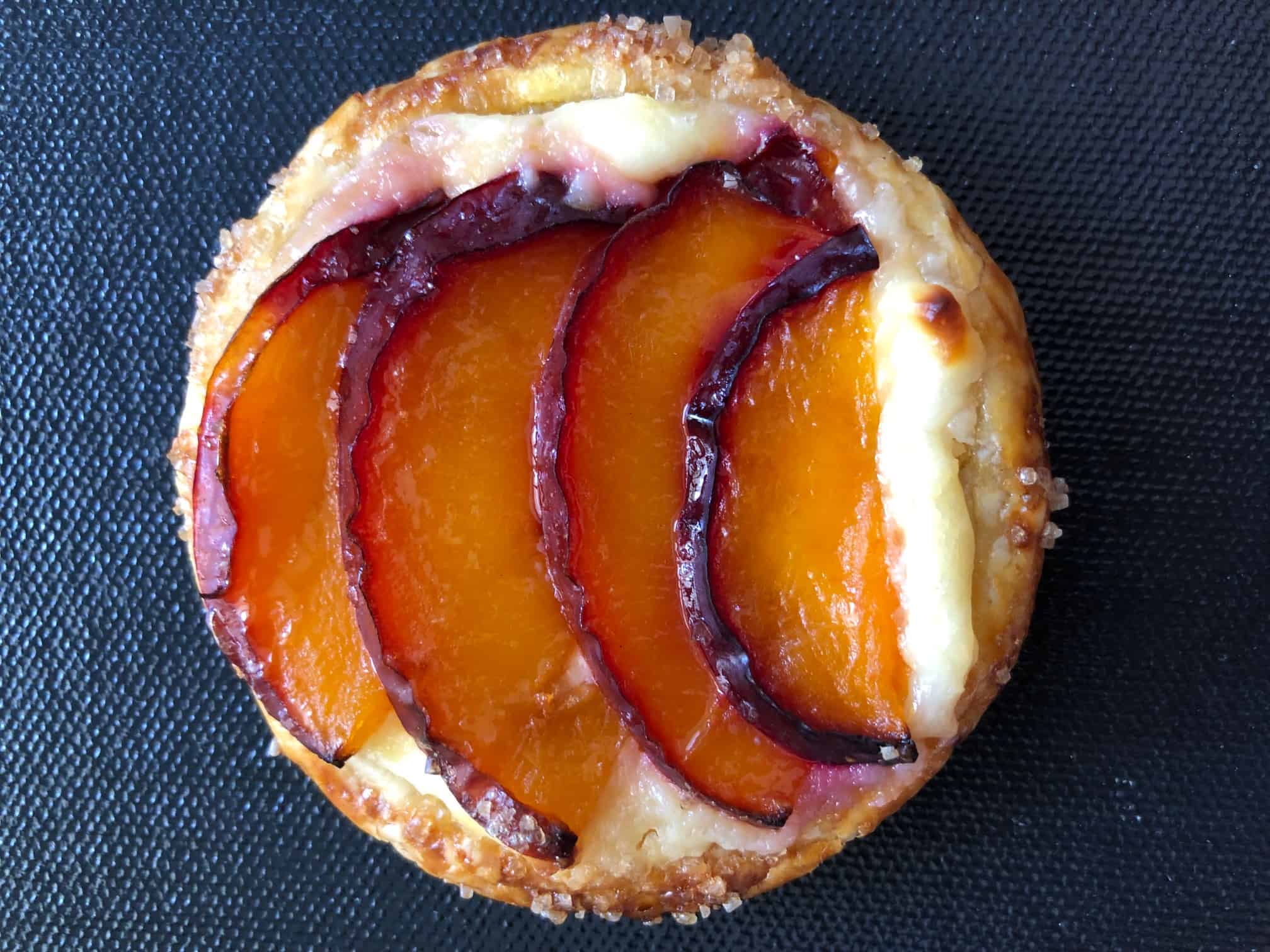 Close up of a mini plum tartlet on a gray background