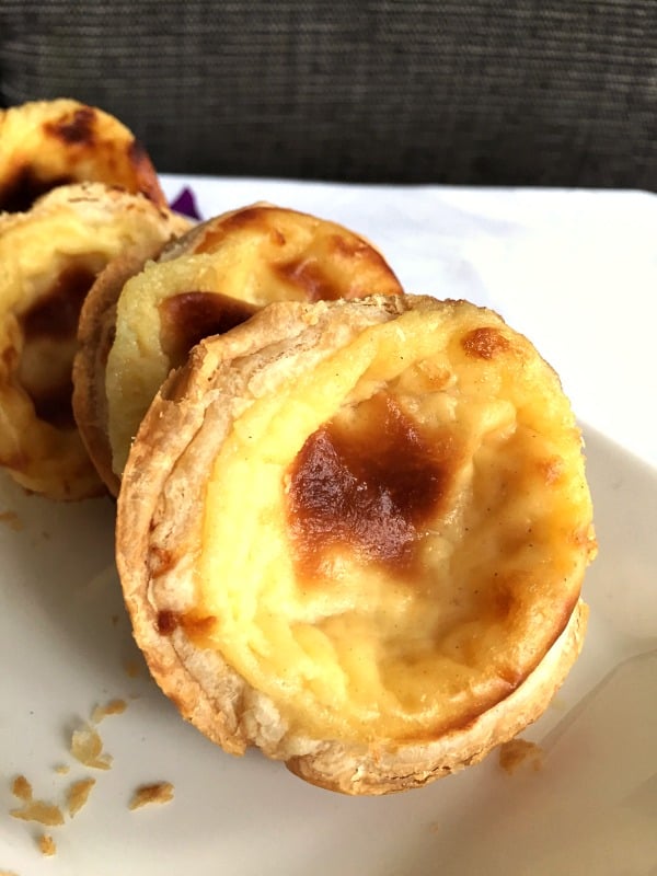 Portuguese Custard Tarts also known as Pastéis de Nata close up on a white dish with a gray background