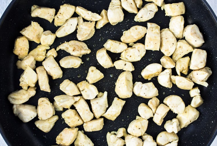 Pieces of chicken cooking in a black skillet