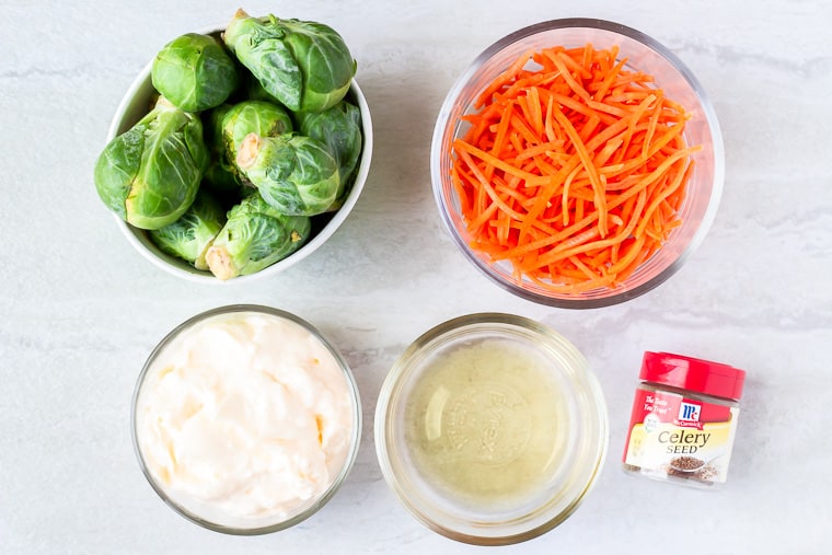 Ingredients for Brussels Sprouts Coleslaw in glass bowls over a white background