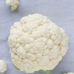 A head of cauliflower on a white background with florets around it