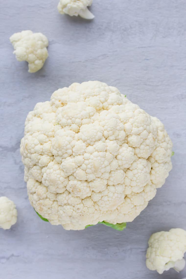 A head of cauliflower on a white background with florets around it