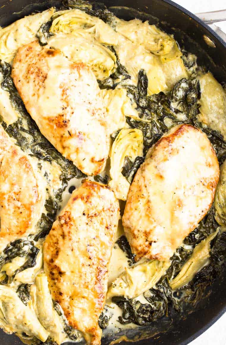 Baked Spinach Artichoke Chicken close up in a black skillet
