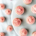 Overhead view of mini strawberry cupcakes topped with strawberry buttercream frosting on a gray cake stand with text overlay.