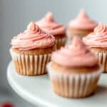 Mini Strawberry Cupcakes topped with strawberry buttercream frosting on a gray cake stand.