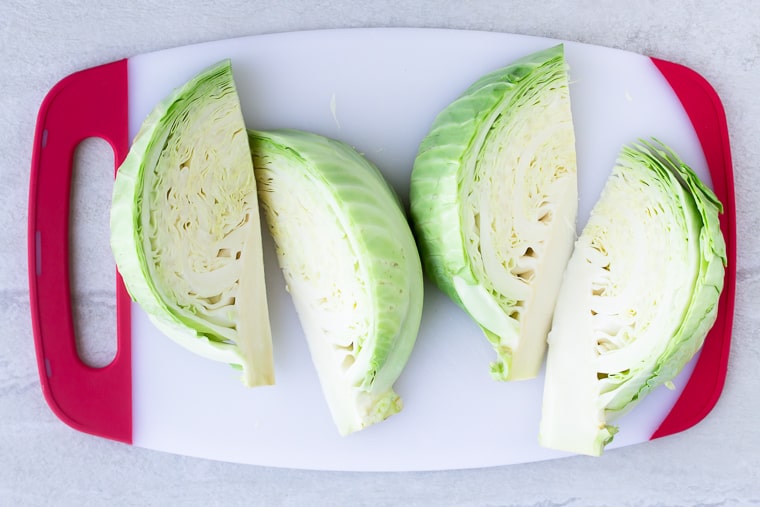 4 Cabbage Wedges on a white cutting board with red handles