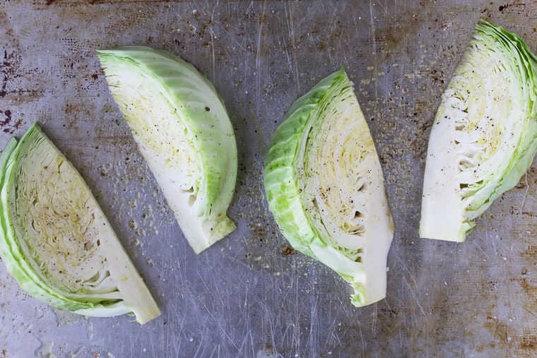 4 Cabbage Wedges on a sheet pan drizzles with oil and seasoned with salt and pepper