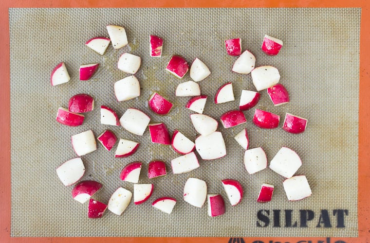 Raw radishes spread out onto a baking sheet