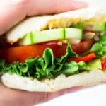 Hand holding a veggie sandwich on an english muffin