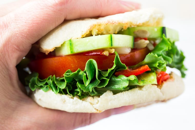 Hand holding a veggie sandwich on an english muffin