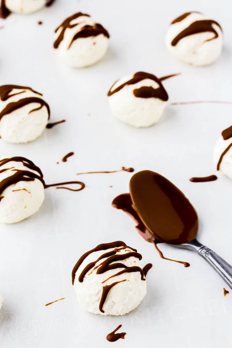 Keto Cheesecake Bites drizzled with chocolate with a spoon covered in chocolate next to them
