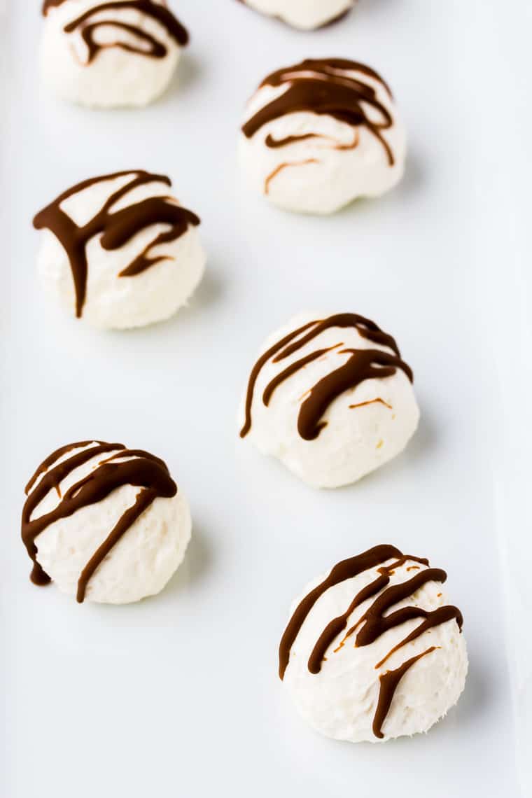 Keto Cheesecake balls on a white tray drizzled with chocolate