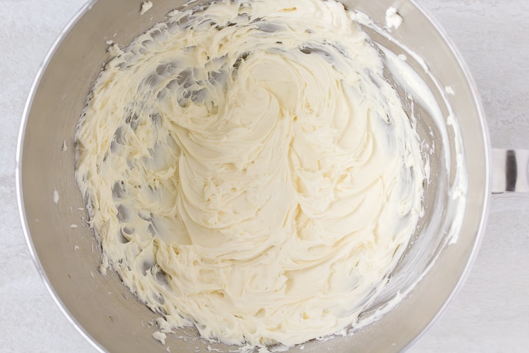 Cheesecake batter in a silver bowl over a white background