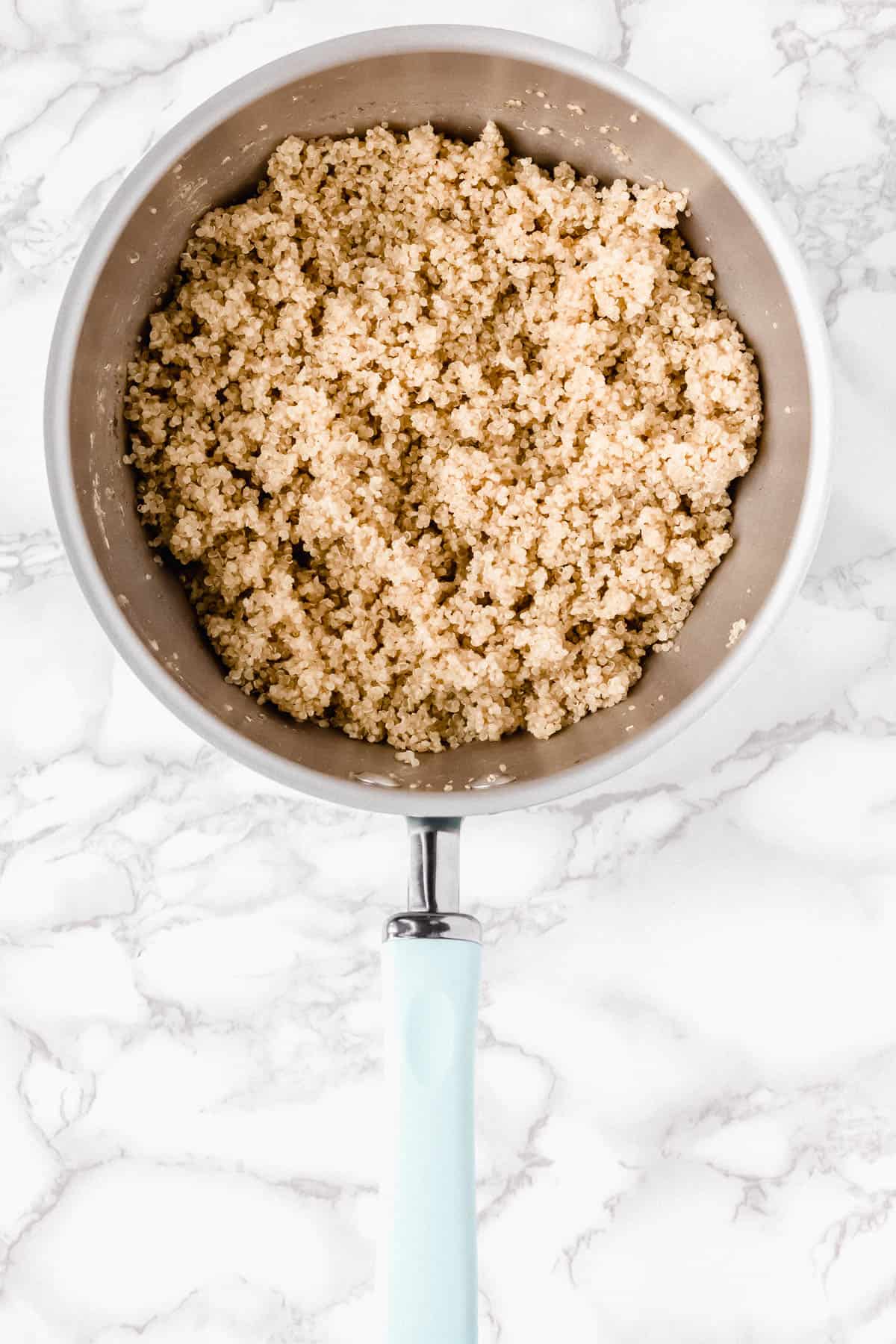 Cooked quinoa in a pot over a marble background
