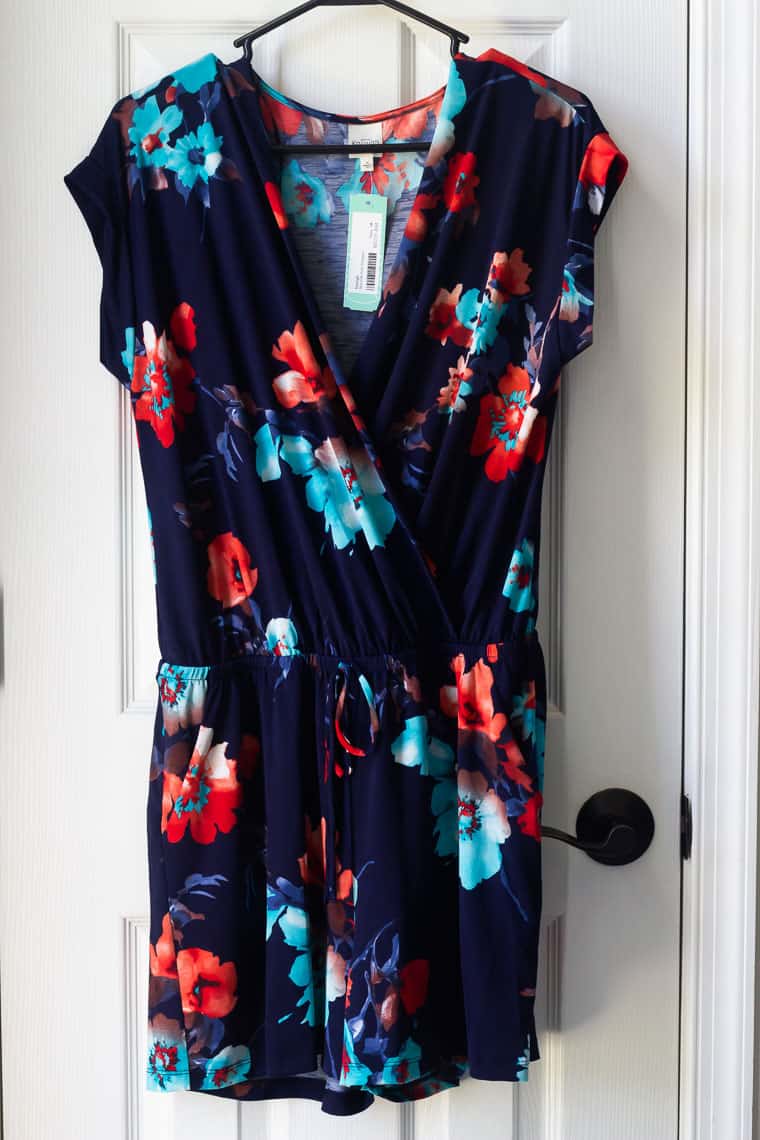 Stitch Fix Kaileigh Marisole Knit Romper in dark blue with a floral print on a hanger over a white door