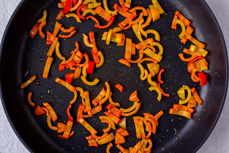 Sweet pepper slices cooking in a black skillet