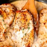 A wood server pushing up a chicken breast with other chicken breasts in creamy dijon mustard sauce around it with text overlay.