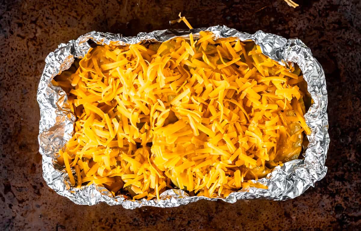 Grilled potatoes topped with shredded cheese in a foil packet.