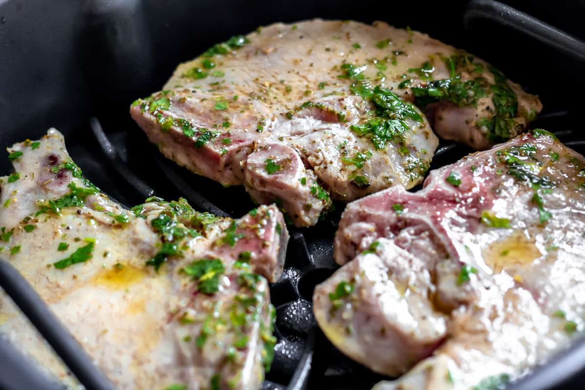 Raw pork chops on a grill.