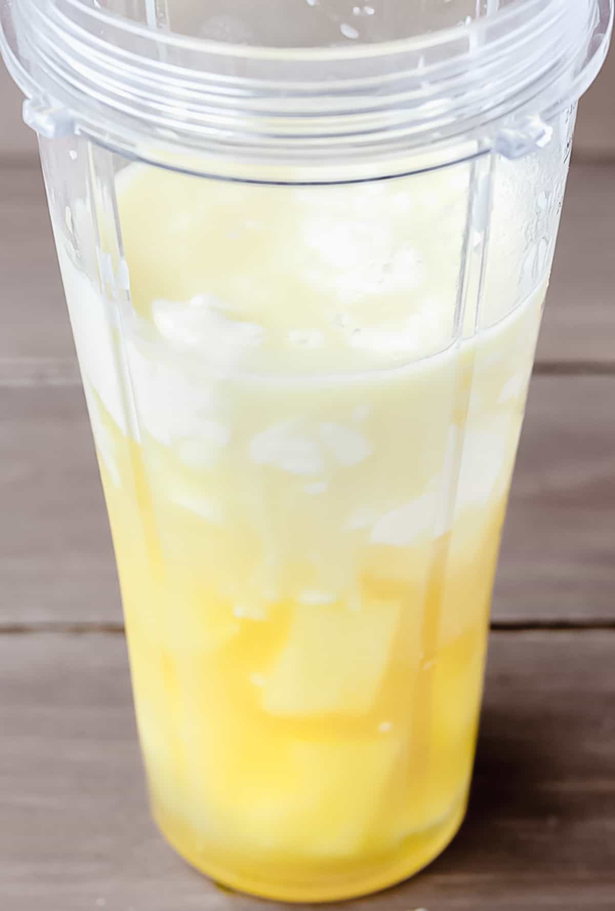 Pineapple smoothie ingredients in a blender cup