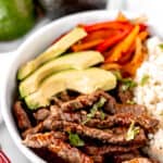 Fajita beef bowl with beef strips, peppers, cauliflower rice and avocado with text overlay.